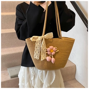 Detail of handmade woven tote bag with lace bow and pink knit flower charm