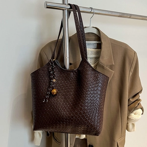 Grand sac cabas tressé chocolat noir avec pendentif doré accroché au cintre