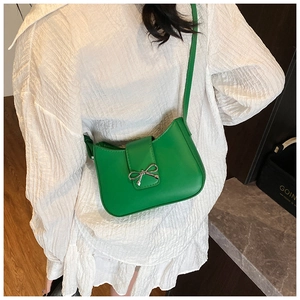 Detail of vibrant green leather baguette bag with silver bow buckle and shoulder strap