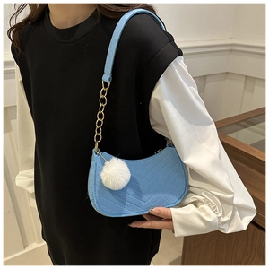 Dettaglio borsa hobo blu con trama trapuntata a V, catena dorata e ciondolo pompon