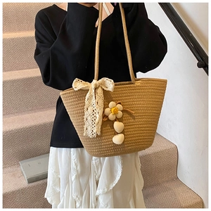 Detailed view of khaki woven tote bag featuring white lace bows and floral charms