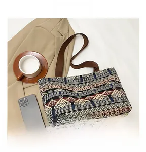 Ethnic printed canvas tote bag with geometric patterns and brown woven handles on desk
