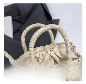 Detail view of handmade beige woven straw bag with sturdy round handles and inner drawstring