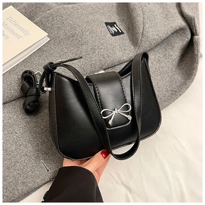 Macro detail of black crescent baguette bag featuring a silver metal bow buckle