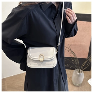 Close-up of beige crossbody bag with gold U-shaped metal lock and precise stitching
