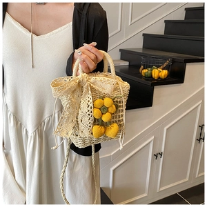 Handwoven straw bag with lace bow and yellow knit floral charms on a modern staircase