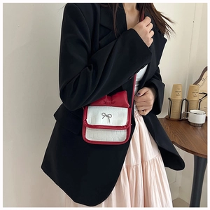 Close-up of contrast crossbody bag featuring red bow detail and crocodile embossed texture