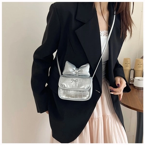 Detail view of silver crocodile embossed mini bag with bow decoration on a model