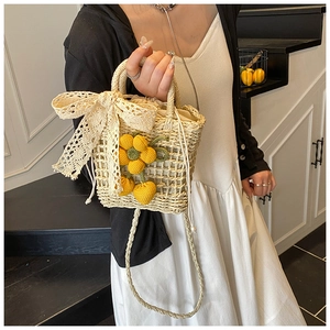 Detail of hand-woven straw bag featuring lace bow, crochet flower, and cherry charms