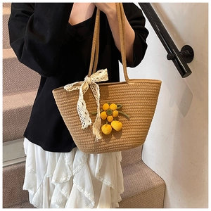 Macro view of woven straw tote bag with lace bow and knitted floral charms detail