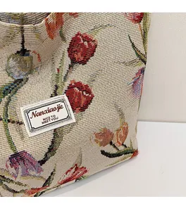 Close-up of jacquard woven tote bag featuring red tulips and a white brand label