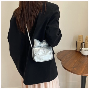 Silver bow-knot mini crossbody bag with crocodile texture shown on a female model