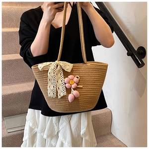 Detail of hand-woven straw bag featuring delicate lace bow and colorful floral charm