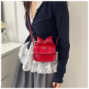 Close-up of red mini crossbody bag with crocodile pattern and large decorative bow