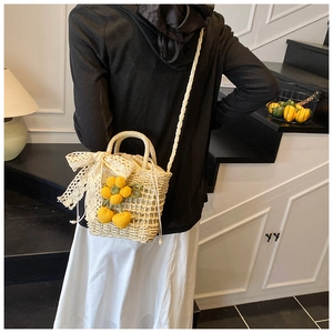 Detail of hand-woven straw bag featuring yellow crochet flower and white lace bow decoration