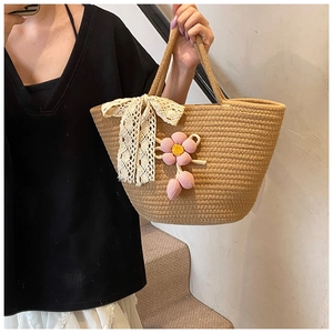 Detailed macro of handwoven straw bag featuring delicate lace bow and crochet floral charms