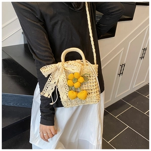 Detail of straw woven bag with lace bow, yellow crochet flowers and cherry accents