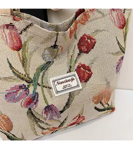 Detailed close-up of knitted tulip pattern tote bag with decorative brand logo label