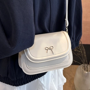 Beige minimalist crossbody bag with silver metal bow accent and layered flap cover