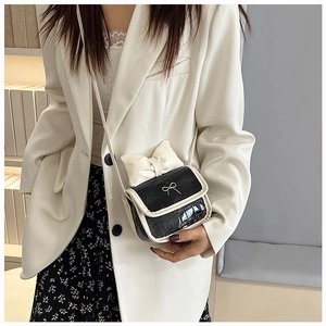 Detail of mini black faux crocodile crossbody bag with white bow and metal buckle