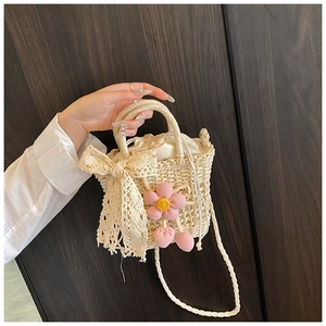 Detail of hand-woven straw bag with pink knitted flower charms and lace ribbon accent
