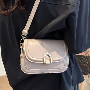 Modern cream PU leather flap crossbody bag with golden horseshoe buckle worn by model