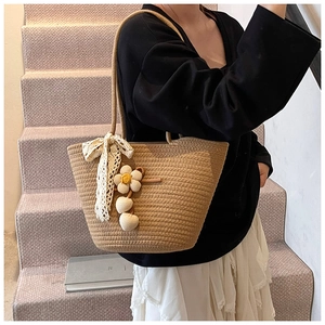 Detail of handmade straw bucket bag with white lace bow and floral 3D decorations