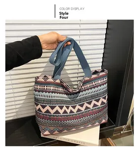 Detail of bohemian geometric woven tote bag featuring blue cotton strap handles