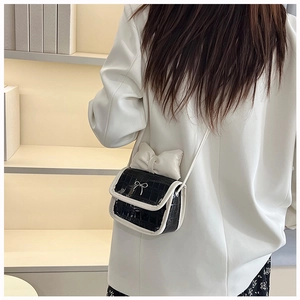 Detail shot of mini crossbody bag with crocodile texture, contrast trim, and bow accents
