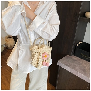 Detail of hand-woven cream bucket bag with lace bow and plush flower charm