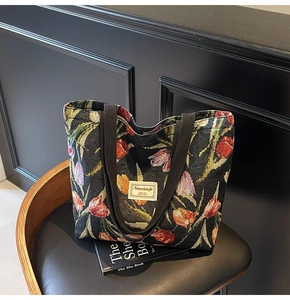 Detailed close-up of a vintage black tapestry tote bag with colorful tulip jacquard patterns