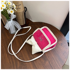 Detail of a bright pink mini bag with a large white bow on a rustic wooden table