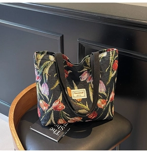 Detail of floral jacquard tote bag with tulip patterns and woven handles on a leather stool
