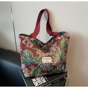 Detail view of jacquard floral tote bag showing premium tropical fabric and red handles