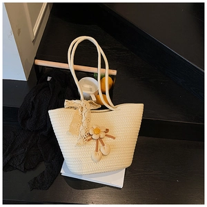 Detail of cream woven tote bag featuring handmade crochet flowers and lace bow accents