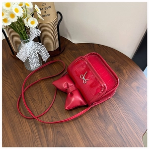 Detail of red patent leather mini bag with crocodile texture and metallic silver bow