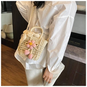 Close-up of woven straw bag with crochet flowers and lace bow on a white shirt