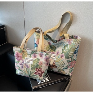 Detailed macro view of retro floral tapestry tote bags with woven handle on a book