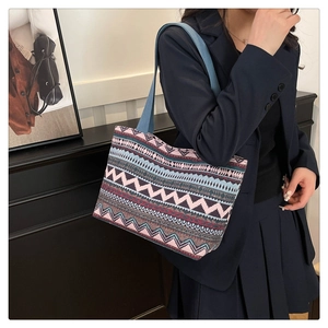 Ethnic canvas tote bag with geometric patterns worn by a model in a navy blue suit