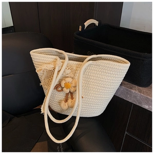 Detail view of woven bucket bag with lace bow and plush floral charms on a black chair