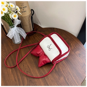 Detailed view of red and white mini crossbody bag with crocodile pattern and bow accent