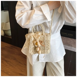 Detail of hand-woven straw bag with lace bow, floral charm and drawstring lining