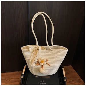 Detail of white woven tote bag featuring delicate lace bow and floral charm accessory