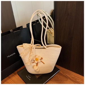 Detailed macro of a cream woven bucket bag featuring lace bows and floral pendants