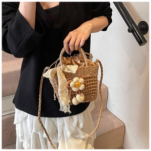 Detail of straw bucket bag with white lace bow and floral charms in a lifestyle setting