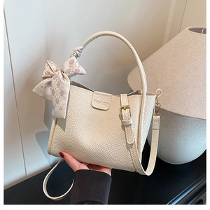 Detail of beige lychee leather bucket bag featuring a Fashion debossing and ribbon