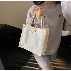 Dettaglio della borsa bento in tela con pizzo bianco e bottone centrale decorativo