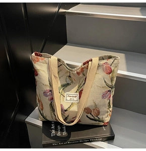 Detailed macro view of tulip floral jacquard fabric and brand label on a large tote bag