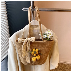 Detail of woven straw bucket bag with floral crochet charms and beige lace bow detail