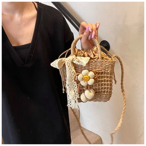 Detail of woven straw bucket bag featuring lace bow and knit sunflower charms
